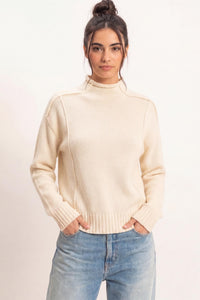 Remy Roll Neck Reversed Seam Sweater in Cream — front view on model