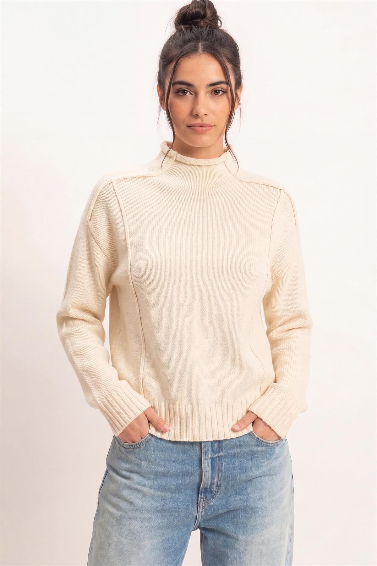 Remy Roll Neck Reversed Seam Sweater in Cream — front view on model