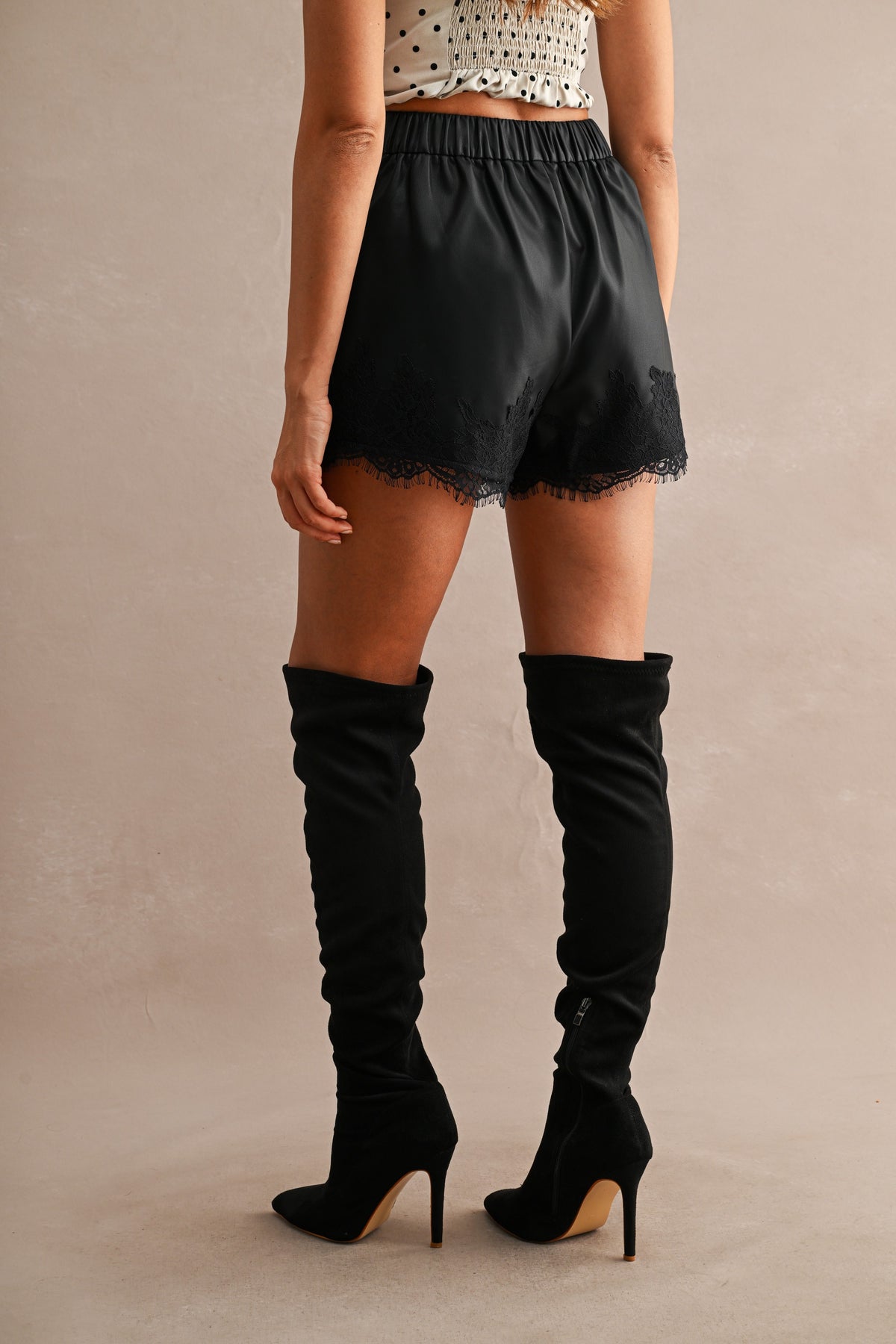 Faux Leather Lace Trim High-Waist Shorts in Black — side view showing high-waisted fit and lace trim hem