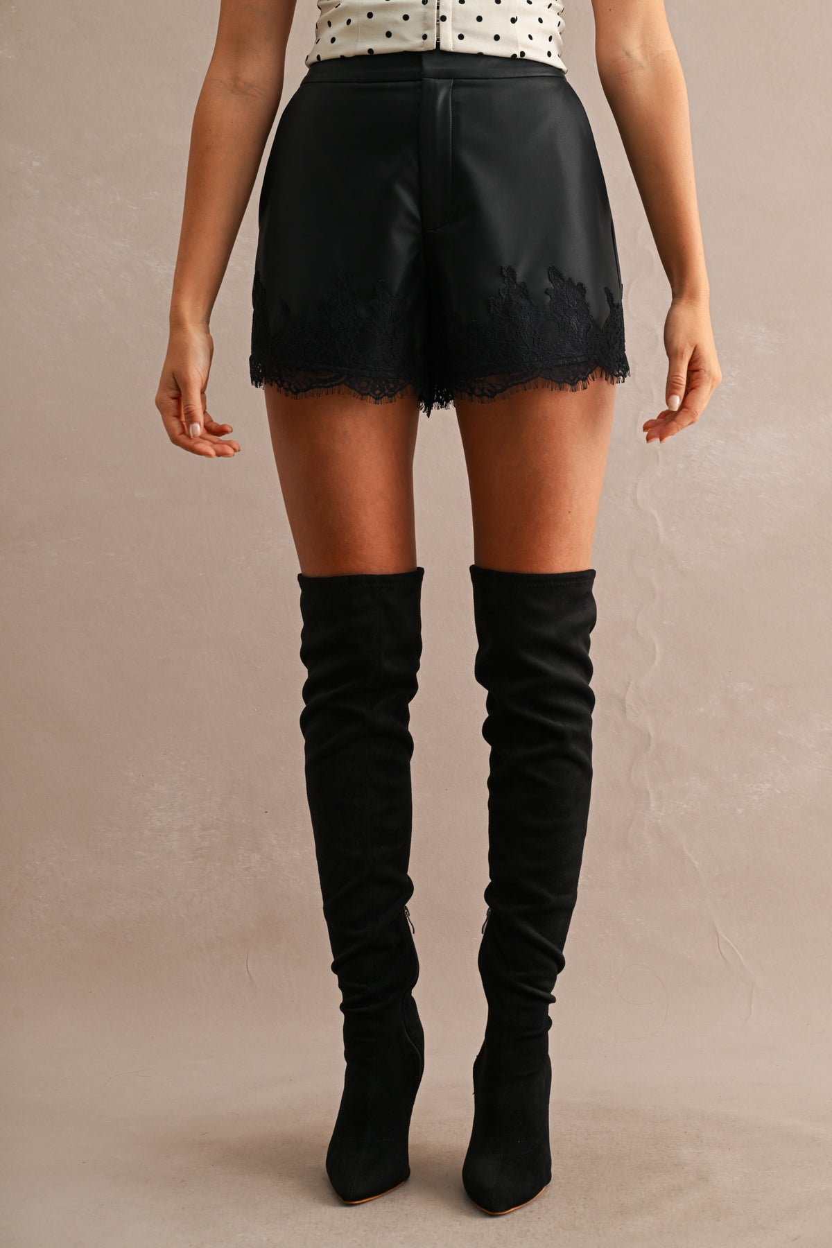 Faux Leather Lace Trim High-Waist Shorts in Black — close-up of contrast lace trim hem detail